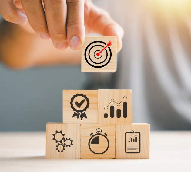 Hand placing a target block on business performance and quality management blocks